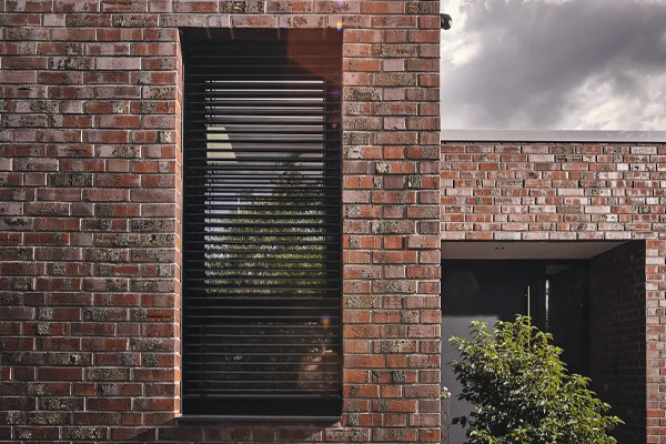 Zwarte buitenjaloezieën bij bakstenen woning